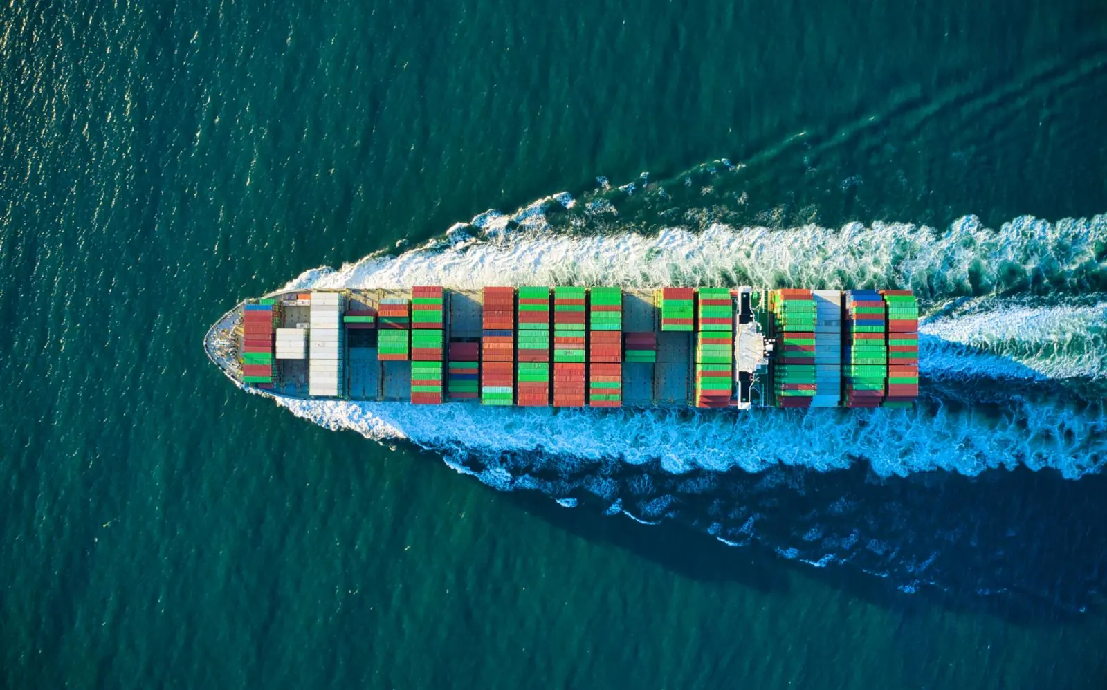Loaded container ship crossing open water, seen from above